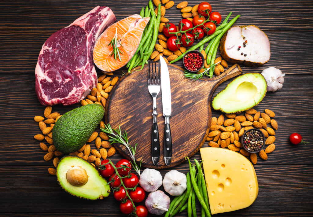 Keto-friendly foods around a cutting board.