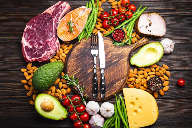 Keto-friendly foods around a cutting board.