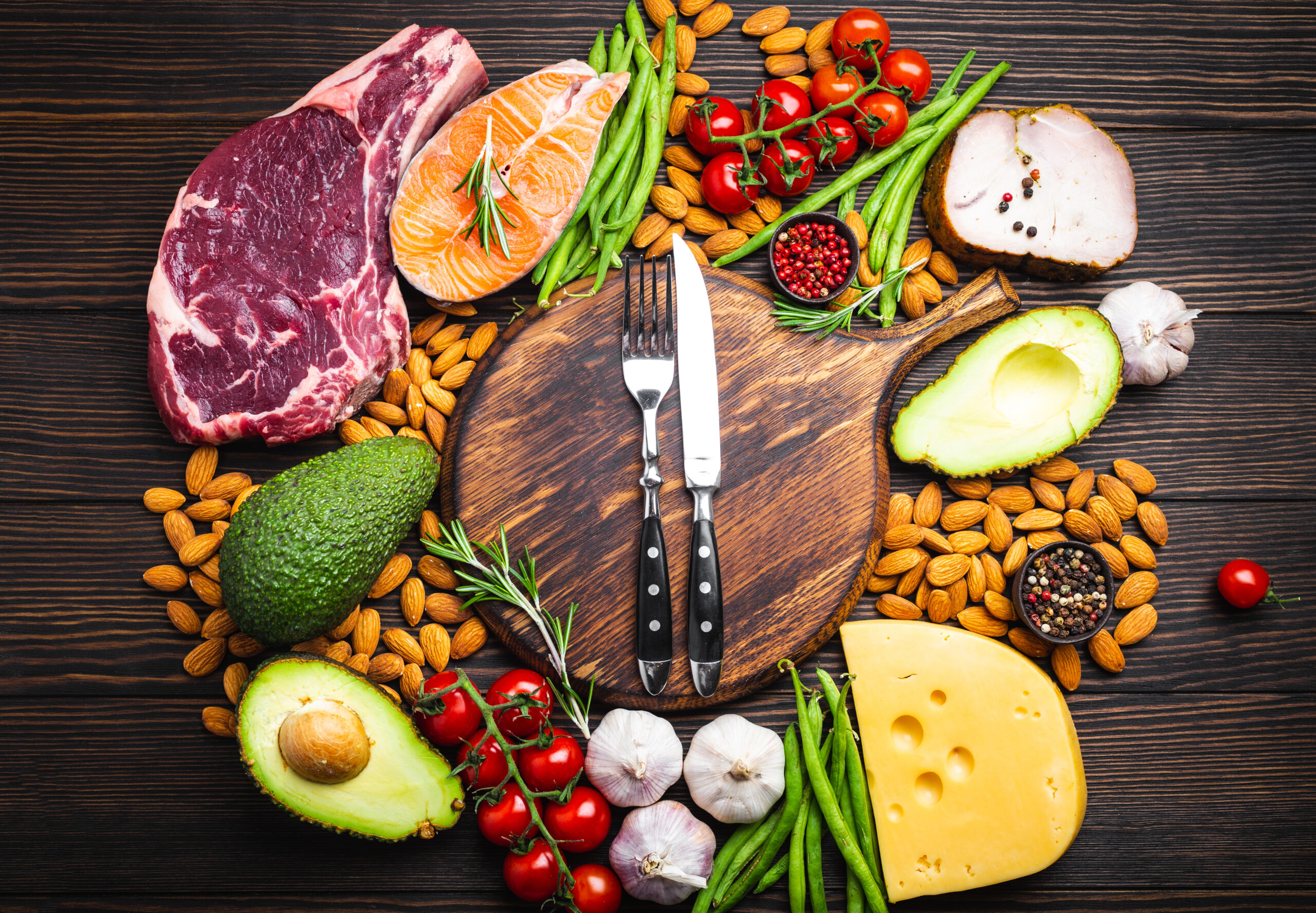 Keto-friendly foods around a cutting board.