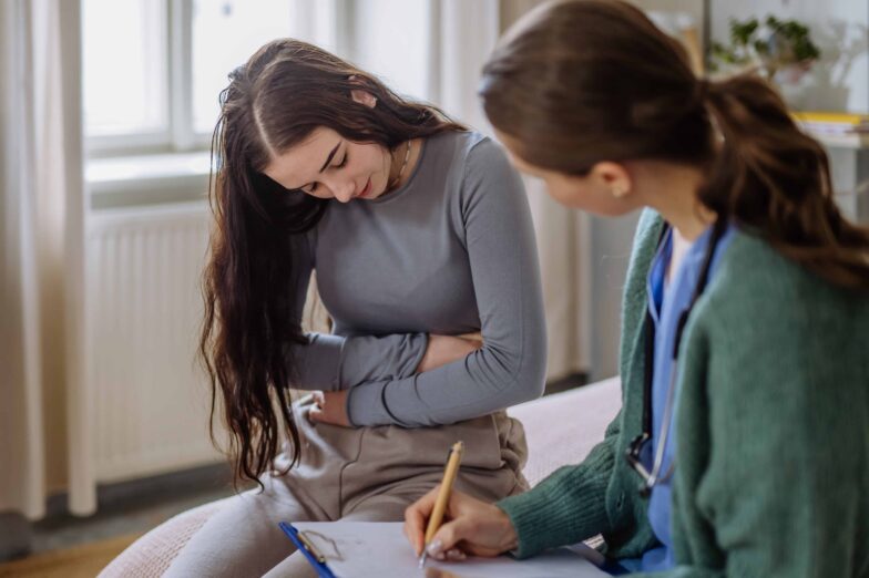 Young woman experiencing symptoms of Disorder of Gut-Brain Interaction, discussing her condition with a doctor