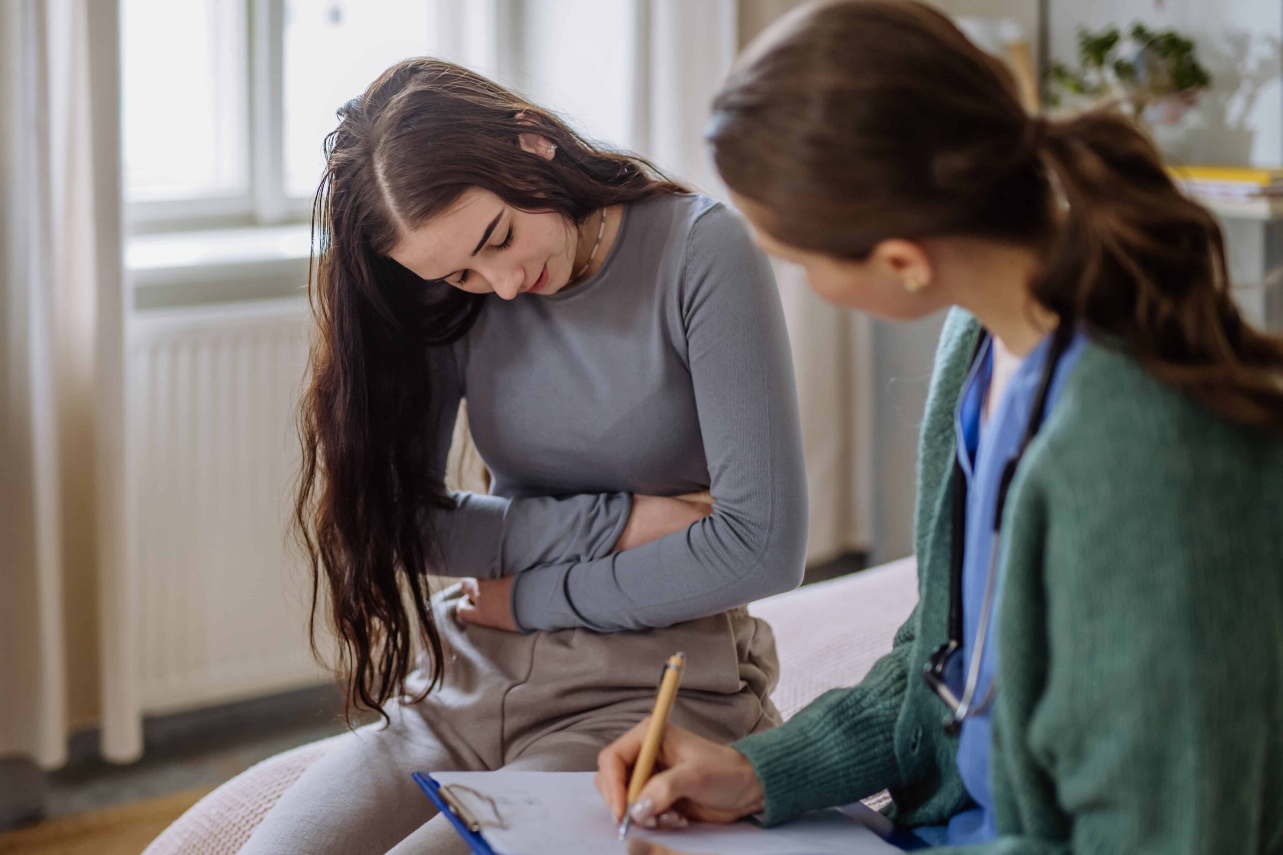 Young woman experiencing symptoms of Disorder of Gut-Brain Interaction, discussing her condition with a doctor