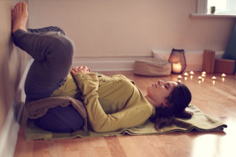Woman practicing diaphragmatic breathing in a restorative yoga pose, illustrating a calming, non-pharmacological approach to GERD relief.