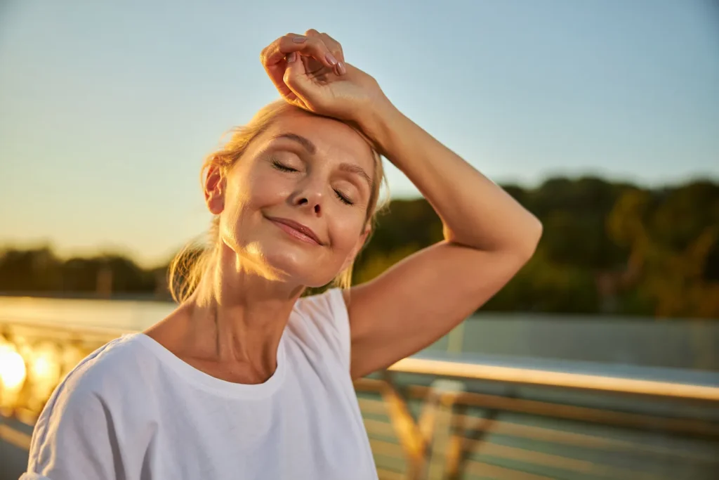 Relaxed middle-aged woman enjoying the sunlight, reflecting the role of vitamin D in supporting health during menopause.
